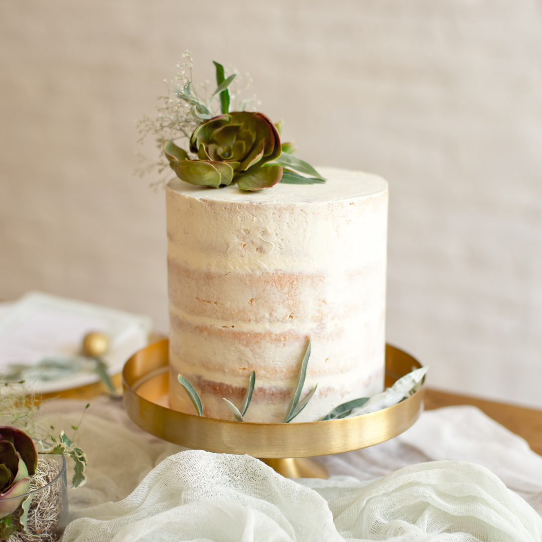 Lightly iced wedding cake on a gold stand